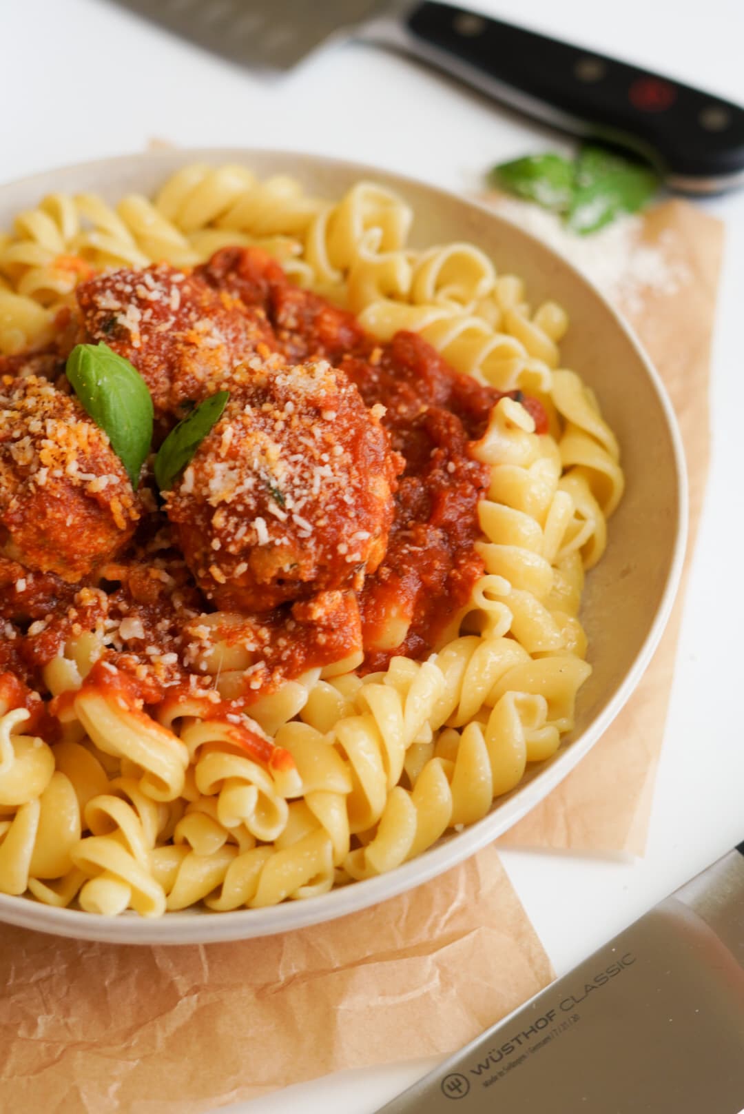 Chicken meatballs with sauce over pasta and WÜSTHOF knife in the background