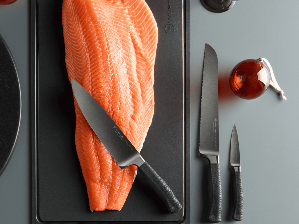 Performer knives on slab of salmon near ornate cup