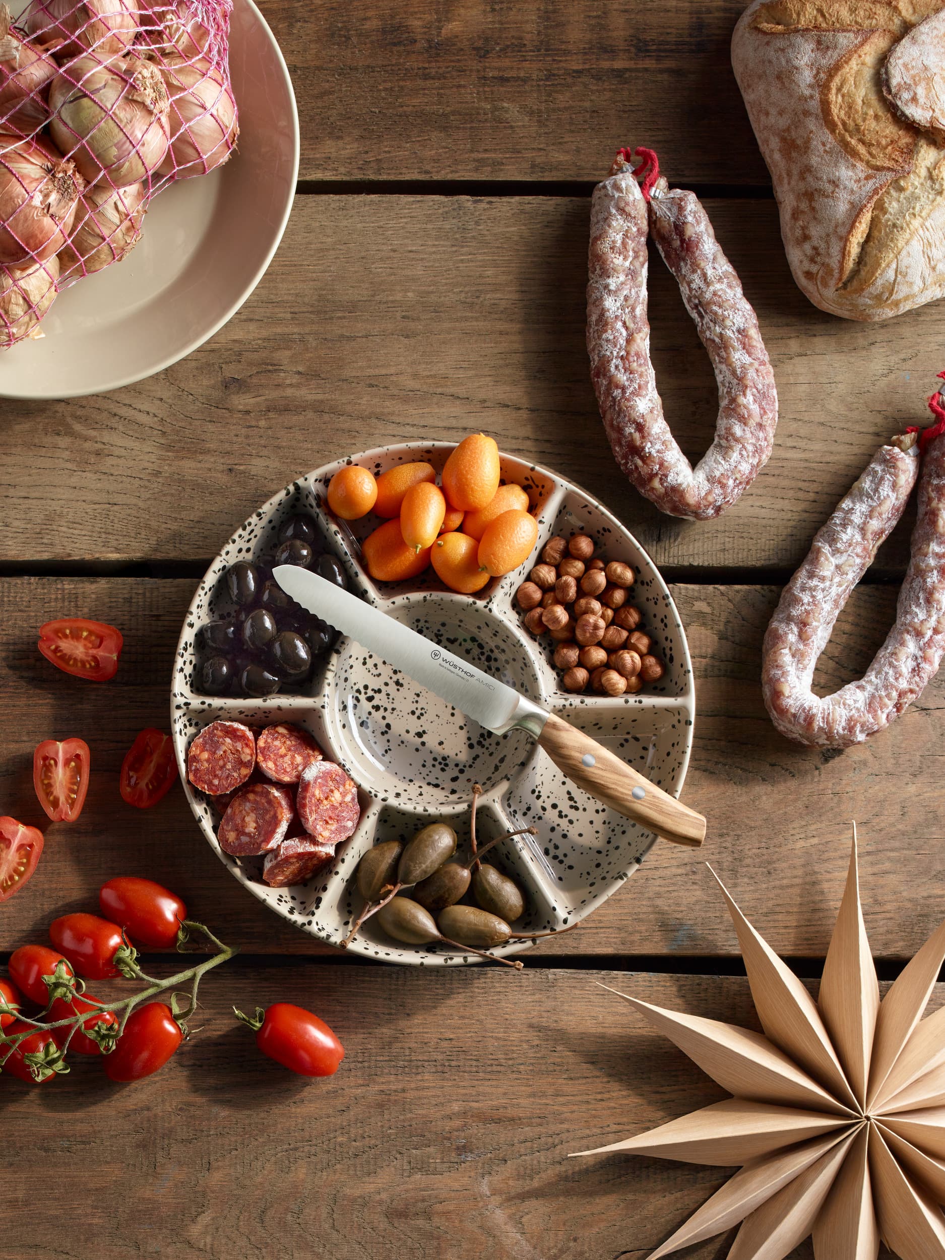 WÜSTHOF amici knife on top of divided bowl with assorted meats, nuts and fruits