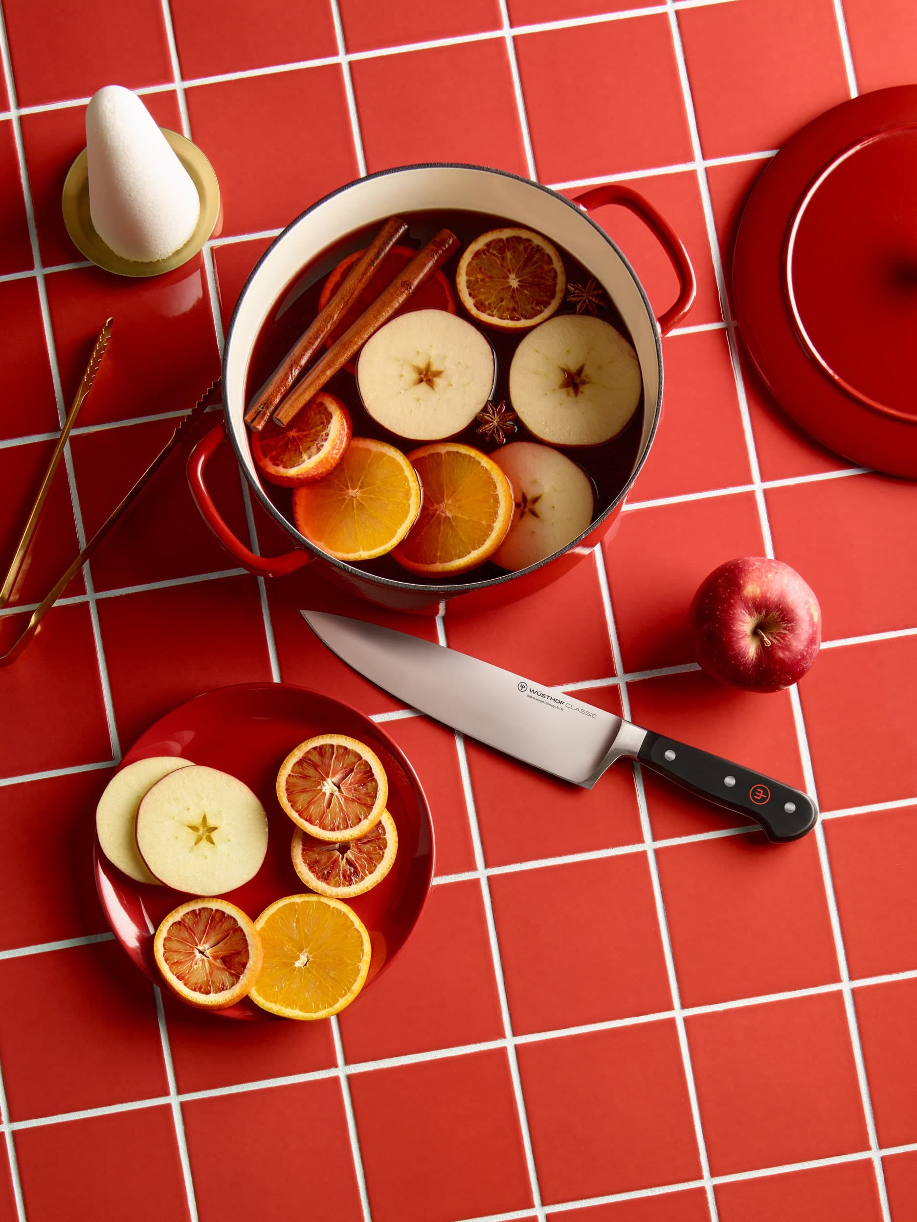 Classic chef knife on red tile counter next to holiday simmer pot