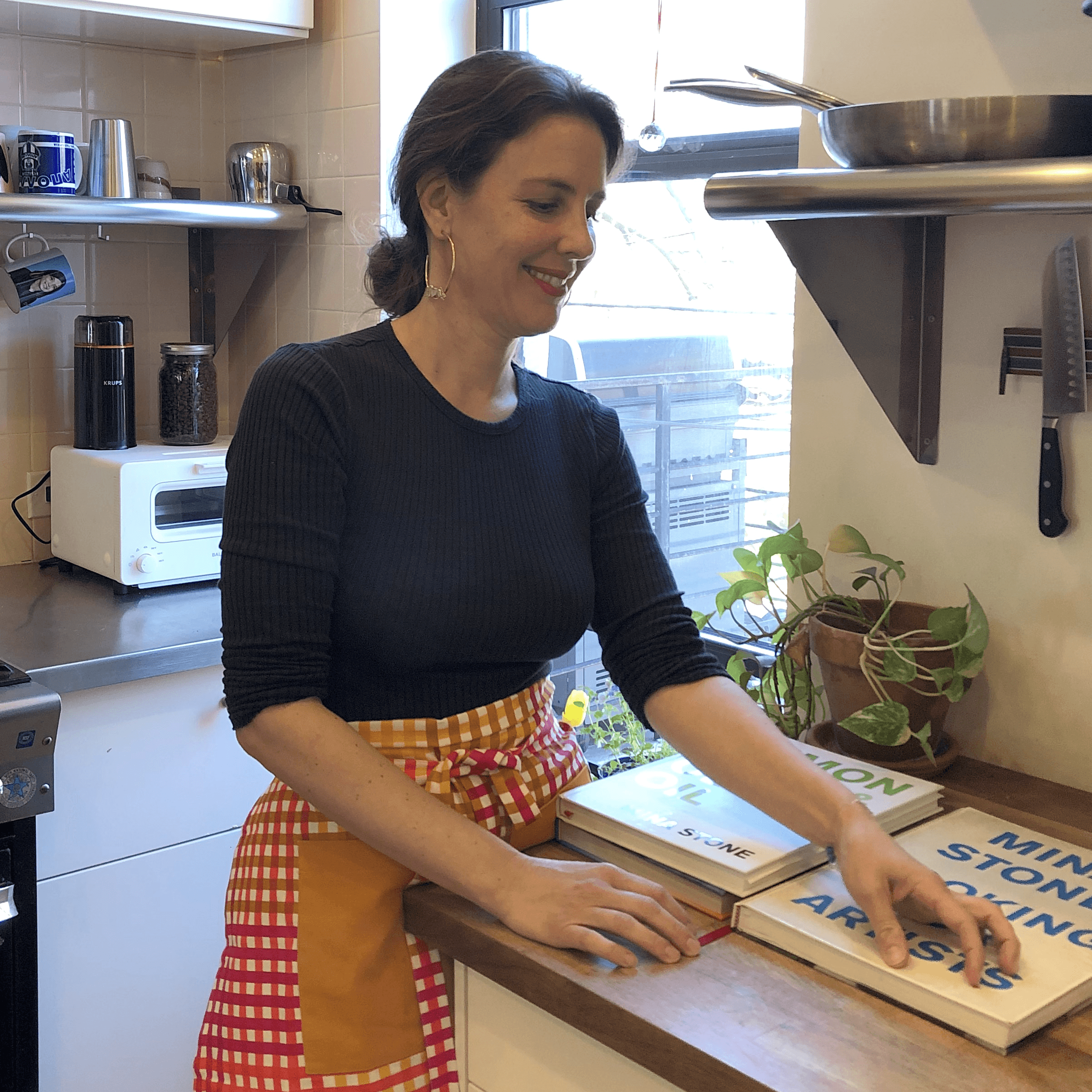 Chef Mina Stone arranging cookbooks in her kitchen.