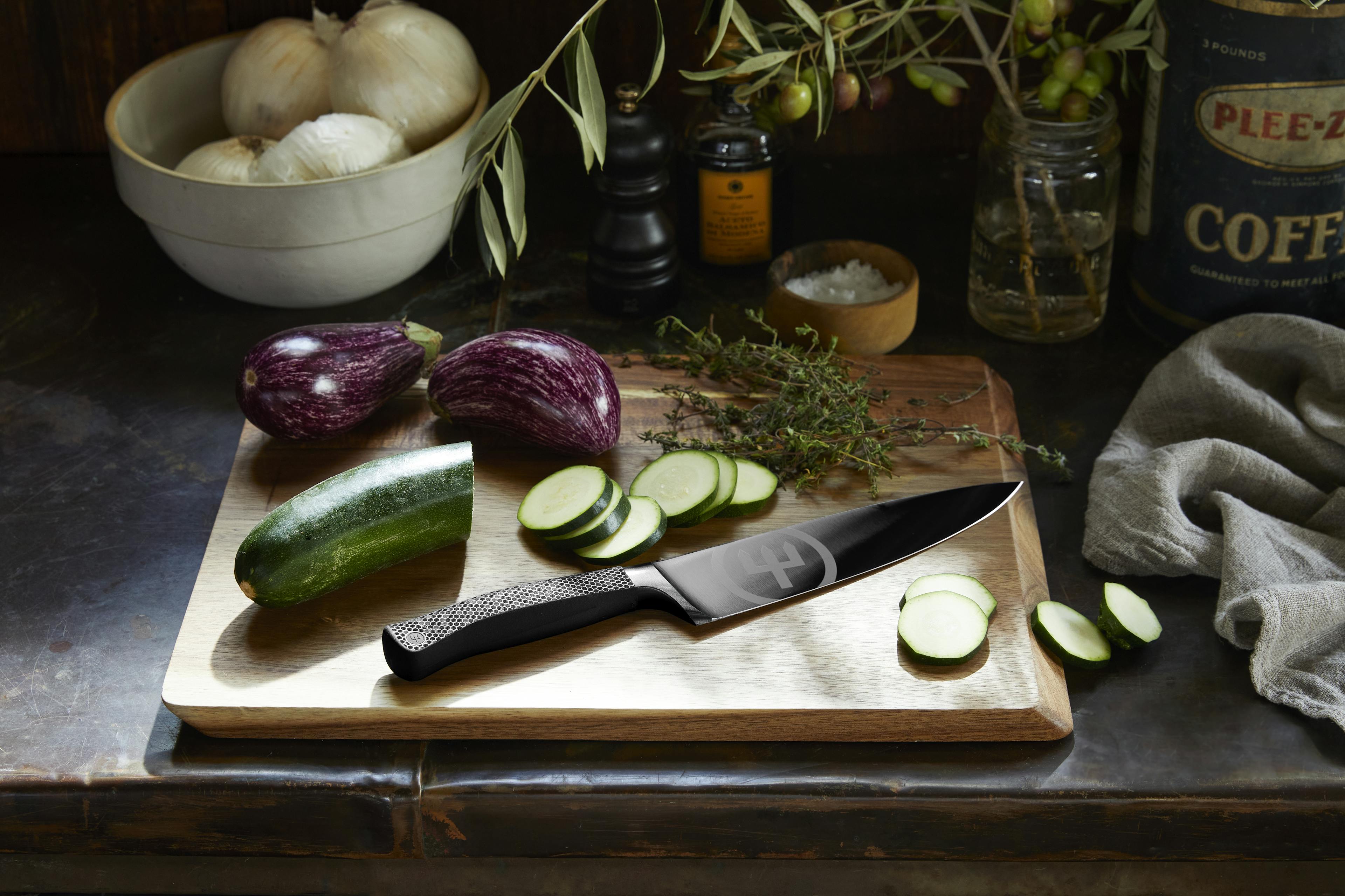 performer knife on cutting board near assorted vegetables
